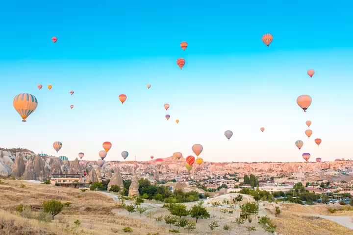 Hot air balloons soar over Cappadocia's unique landscape at sunrise, offering breathtaking views on a private tour.