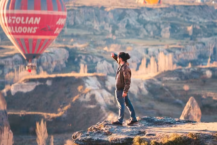 Traveler at Cappadocia viewpoint watching sunrise hot air balloons, part of 9-day Mesopotamia and Cappadocia tour
