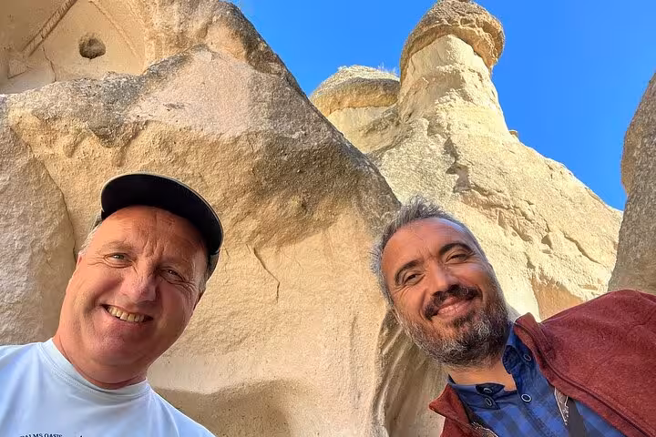 Travelers selfie by Cappadocia fairy chimneys on a full-day small group North Tour near Göreme