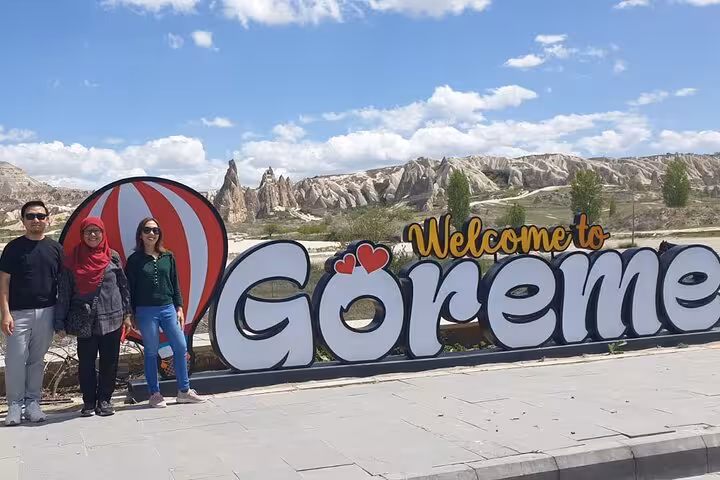 Group photo at Welcome to Göreme sign with Cappadocia valleys on a full-day small group North Tour