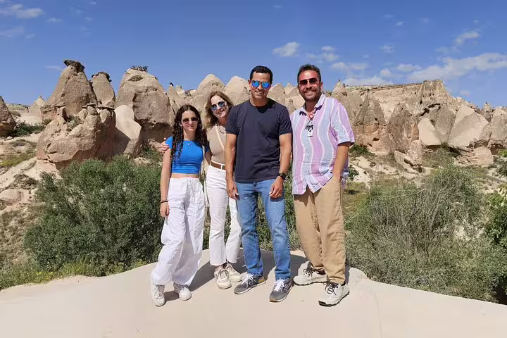Happy travelers posing in front of Cappadocia's unique rock formations during a private tour from local hotels.