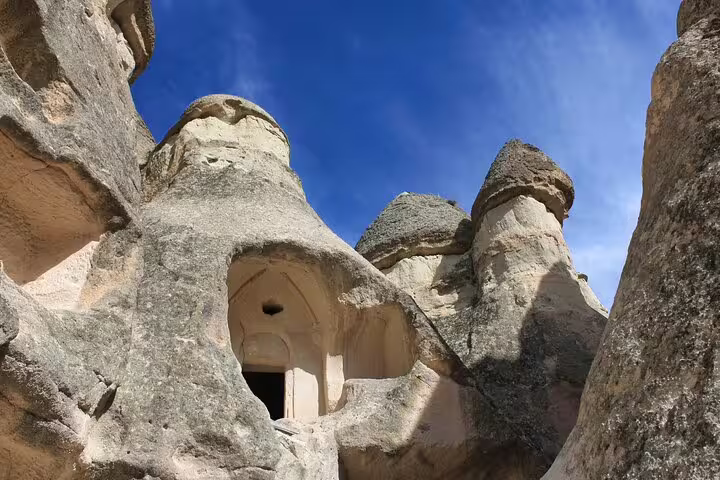 Unique rock formations with ancient cave dwellings under a clear blue sky in Cappadocia private tour experience.
