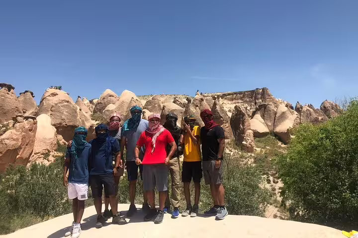 Tourists pose in front of Cappadocia's unique rock formations on a sunny day during a private adventure tour.