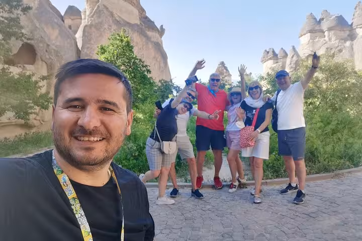 Happy travelers posing on Cappadocia Red Tour small group in Göreme, fairy chimneys and rock caves behind
