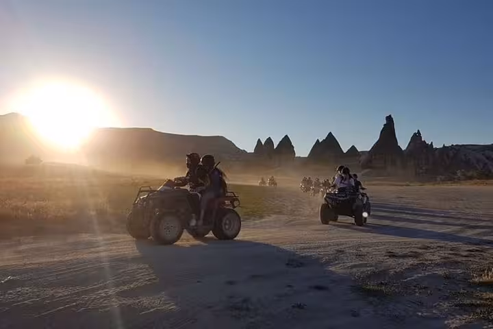 Cappadocia sunset ATV tour riders crossing dusty valley with fairy chimneys on a 2-hour quad safari