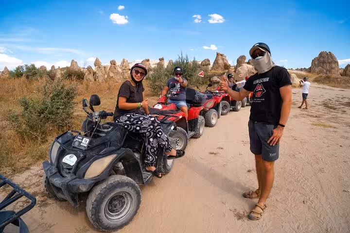 Group photo on Cappadocia sunset ATV tour with guide and riders lined up near fairy chimneys