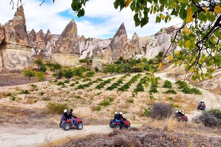 ATV group tour in Cappadocia riding through vineyard valley with fairy chimneys, scenic 2-hour quad safari
