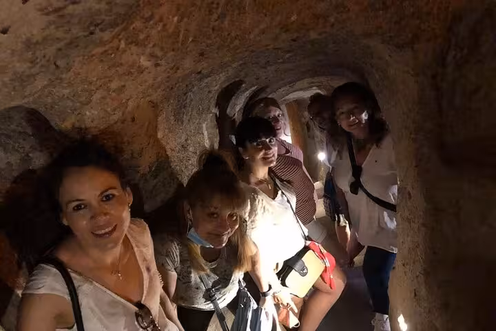 Small group exploring Cappadocia underground city tunnels on guided tour with lunch, narrow cave passageway