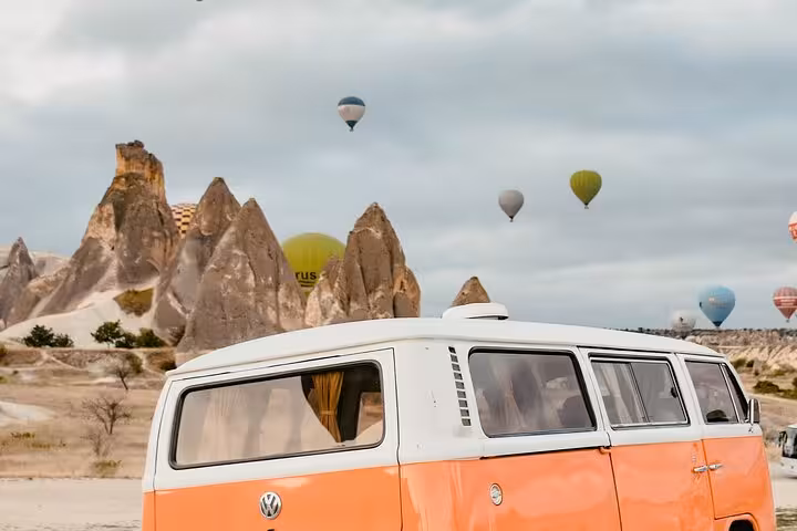 Vintage VW van in Cappadocia with hot air balloons over Göreme on 2-day 1-night Istanbul flight tour and balloon ride