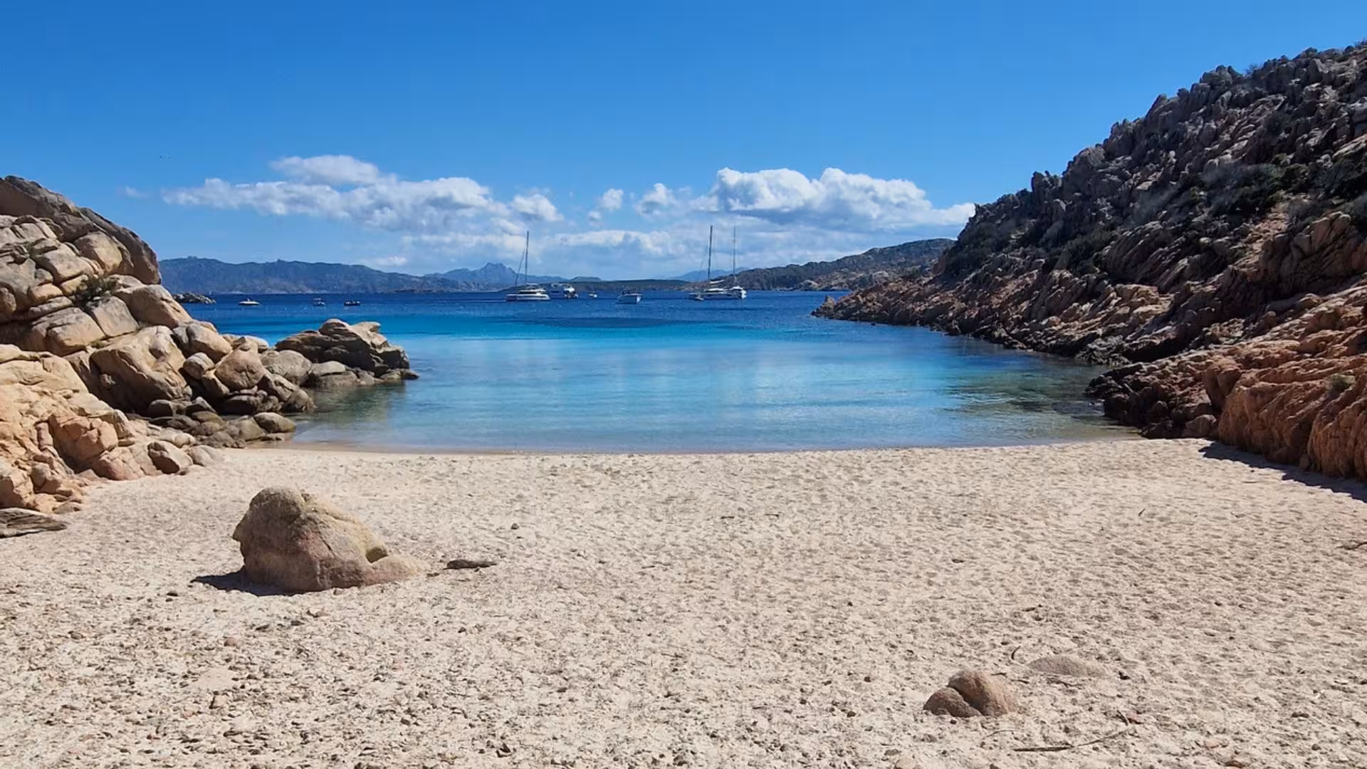 Idyllic Cala Coticcio beach on Caprera Island, featuring clear turquoise waters and rugged rocky landscape.