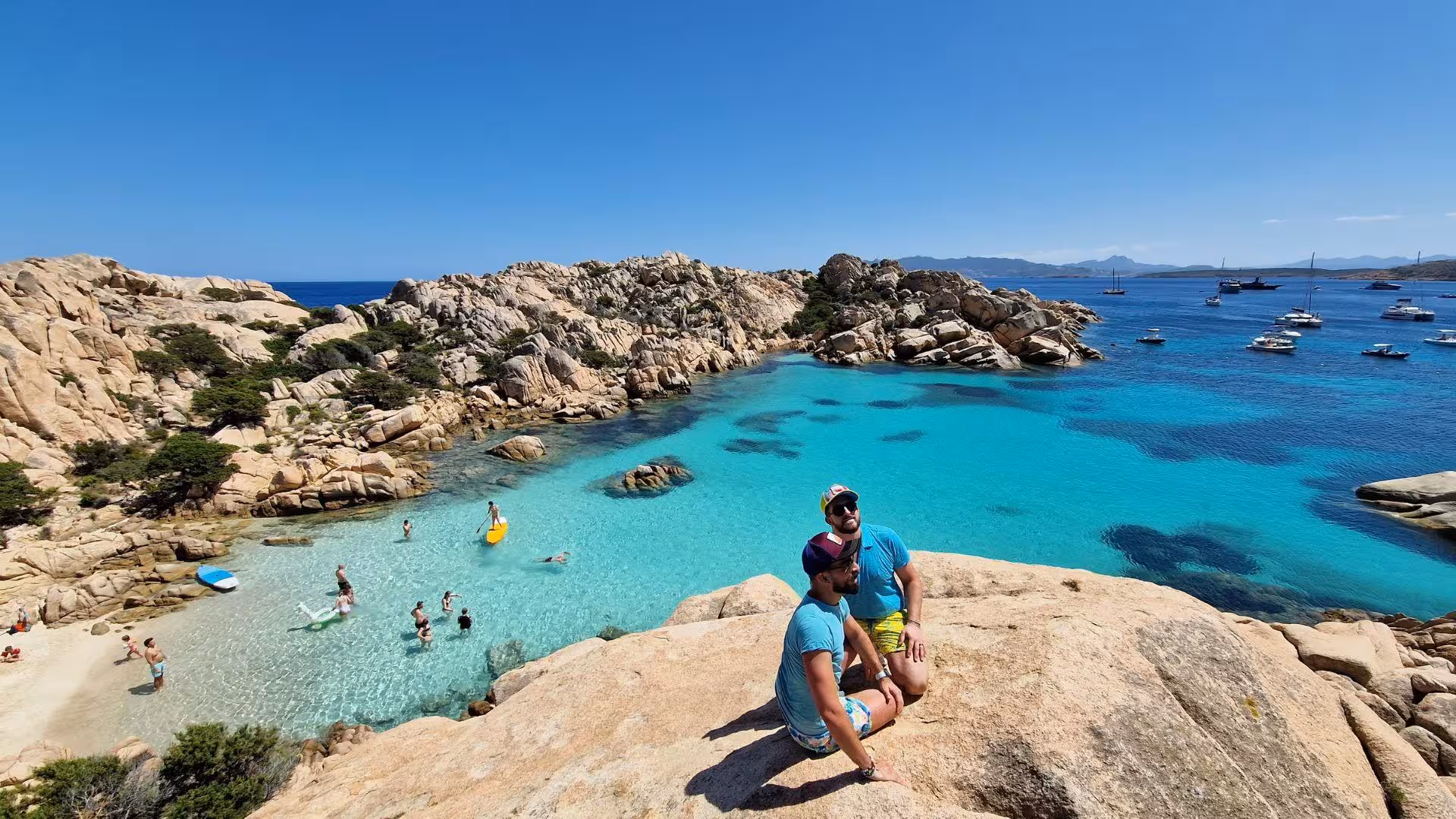 Hikers enjoying stunning views of Cala Coticcio's turquoise waters and rocky landscape on Caprera Island tour.