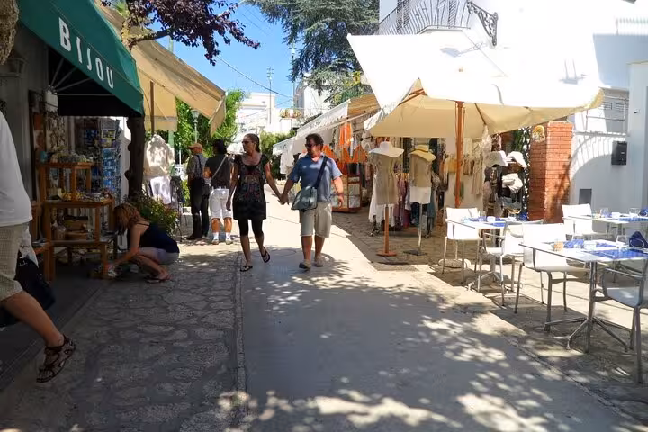Tourists exploring charming streets of Capri lined with boutiques and cafes on Amalfi excursion.