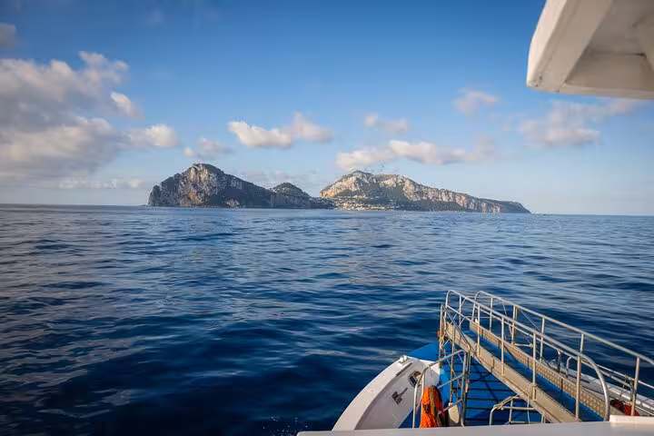 A scenic boat ride offers stunning views of the island of Capri against a backdrop of clear blue skies.