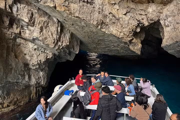 Tourists enjoy a boat tour through a stunning sea cave on the Capri and Anacapri tour from Sorrento.