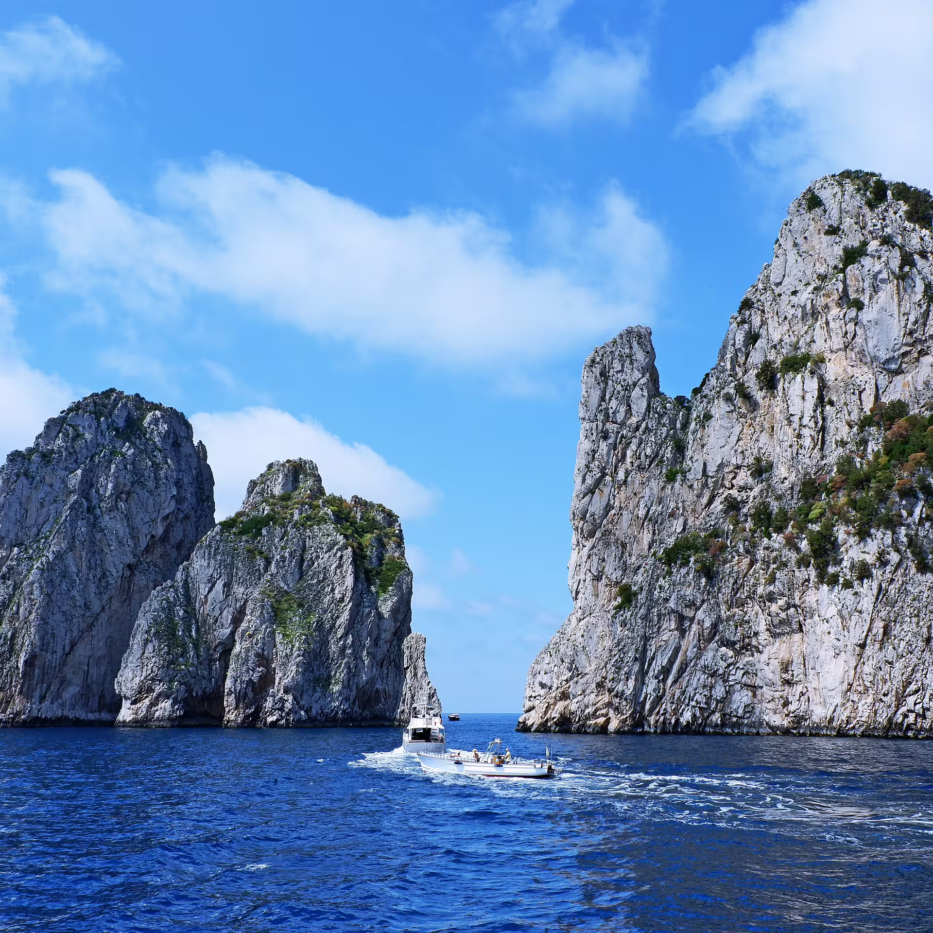 Ferry boat near Capri cliffs and Faraglioni rocks on a Naples small-group Capri and Anacapri day trip with tickets