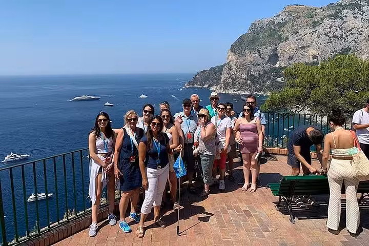 Group of tourists enjoying a scenic view of Capri's coastline on a sunny day during the full-day hydrofoil tour.