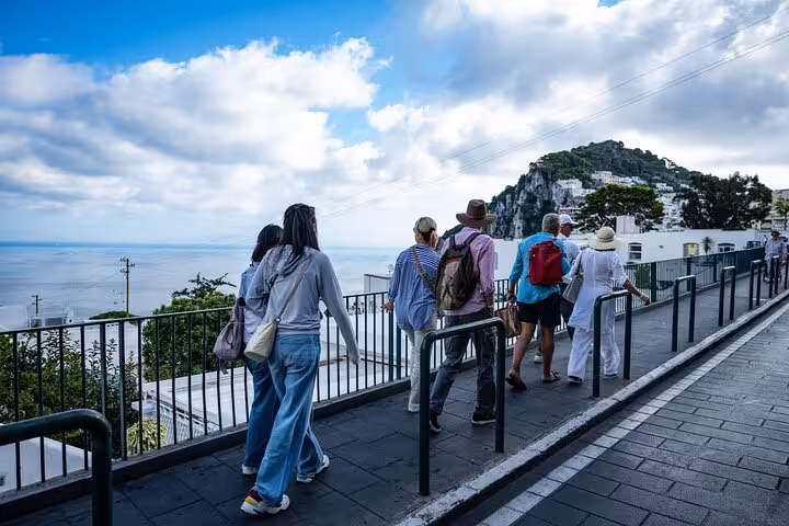 Tourists walking along a scenic path in Capri with stunning sea views, part of the all-inclusive Capri and Anacapri tour.
