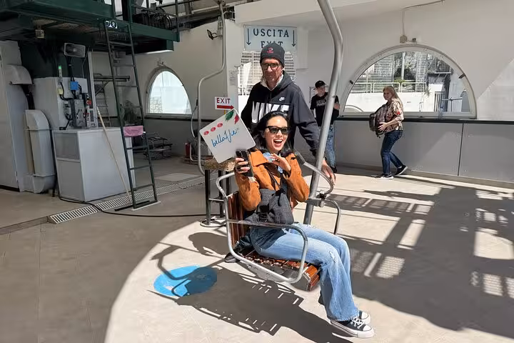 Excited tourist on a chairlift during a Capri shore excursion visiting the Blue Grotto and Faraglioni landmarks.