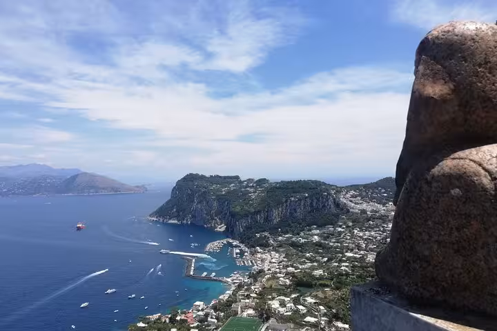 A stunning view of Capri's coastline from a high vantage point, featuring the Blue Grotto and rugged cliffs.