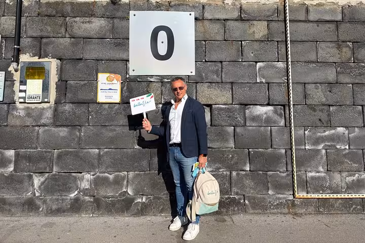 Tour guide holding a sign at the starting point of a Capri shore excursion near the Blue Grotto and Faraglioni.
