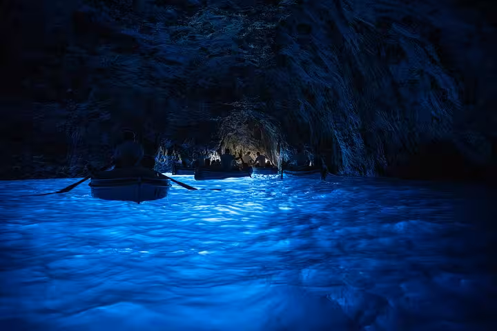 Visitors in rowboats explore the luminescent waters inside Capri's enchanting Blue Grotto cave.