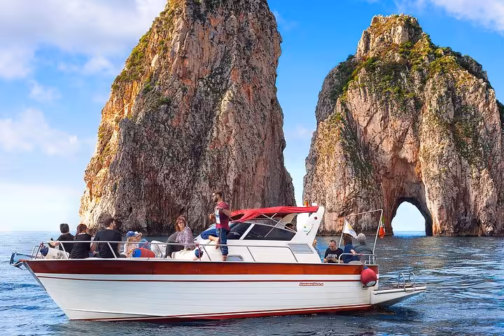 Boat tour approaching the iconic Faraglioni rocks during a small group Capri excursion from Sorrento.