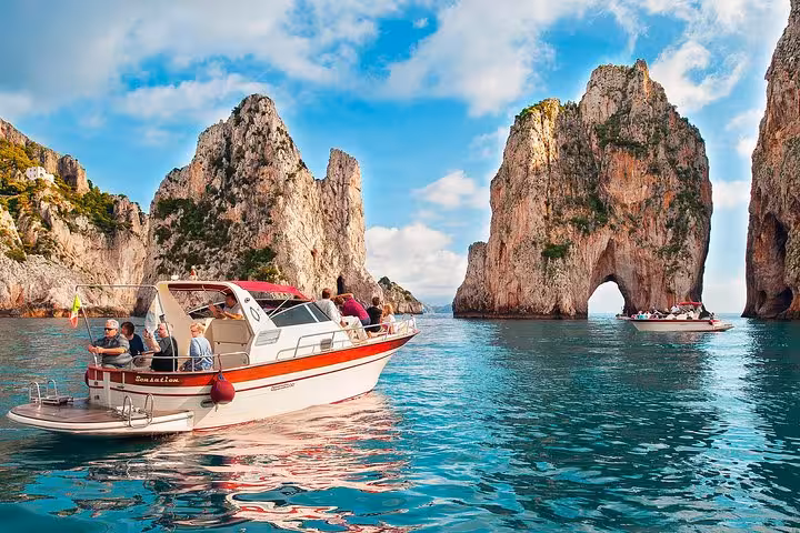 A small group boat cruising near the iconic Faraglioni rock formations on a Capri excursion from Sorrento.