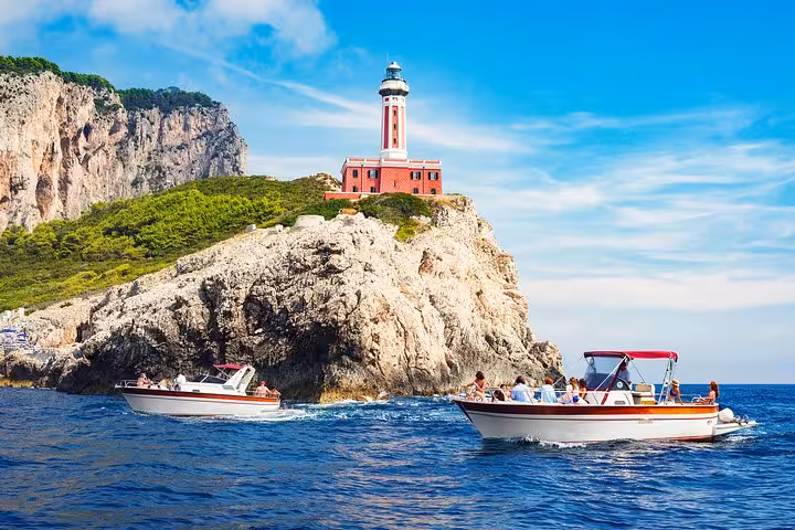 Scenic boat excursion near Capri Island, showcasing a picturesque lighthouse and rugged coastline from Sorrento tour.