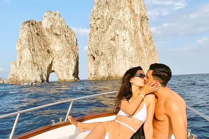Couple kissing on private classic Gozzo in Capri with Faraglioni rocks, romantic 3-hour island tour