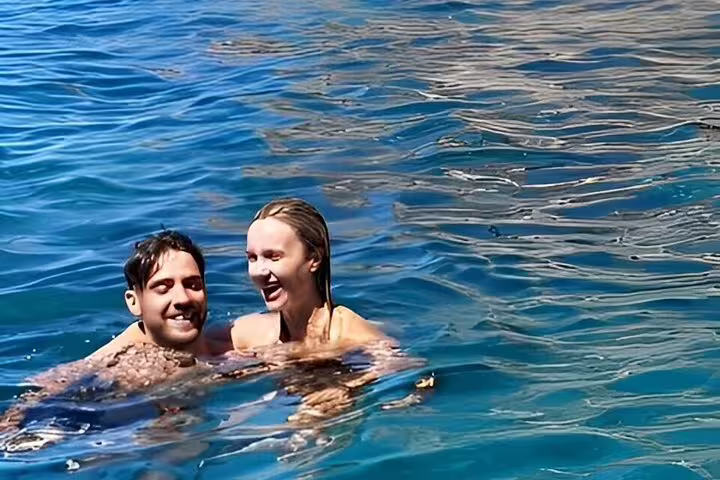 Couple swimming in clear blue water during Private Boat Tour Sea Day Charm and Freedom full-day cruise