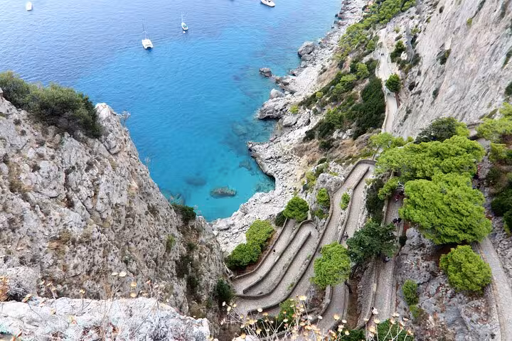 Discover the scenic coastal pathways and turquoise waters of Capri on a Faraglioni shore excursion from Naples.