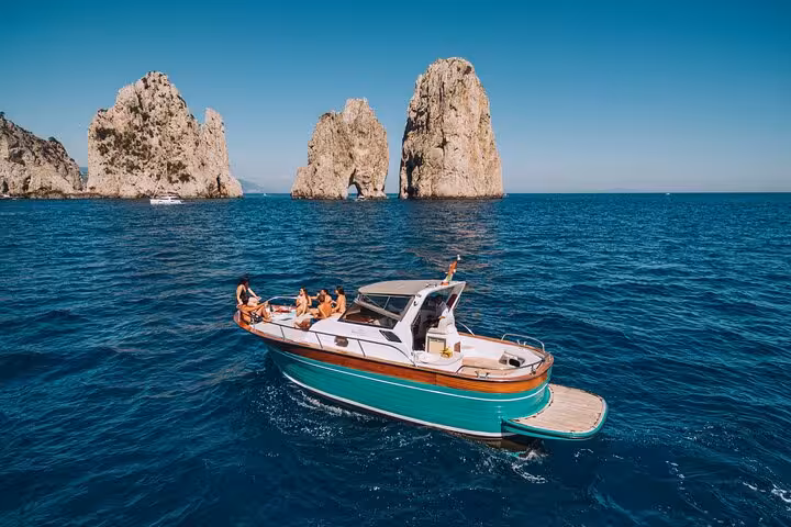 Boat cruising near iconic Faraglioni rock formations on Capri during Amalfi Coast tour.