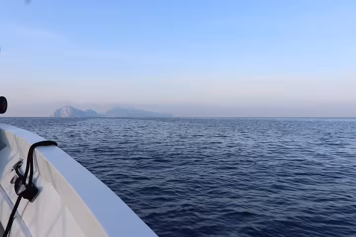 Boat cruising towards distant Capri island on a serene Faraglioni cruise experience.
