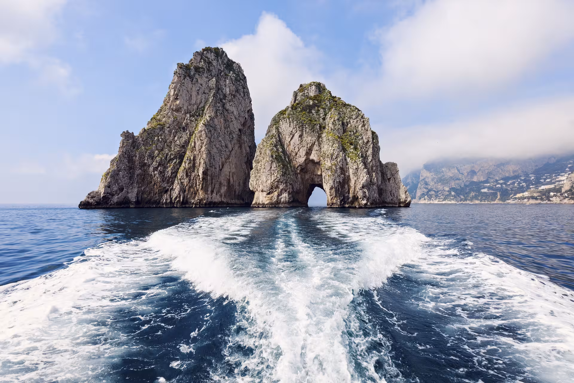 View of Faraglioni rock formations from a boat during Capri tour, highlighting natural beauty and sea adventure.