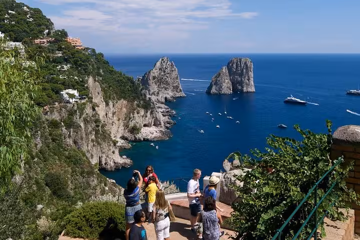 Tourists admire the stunning Faraglioni rock formations on a sunny day during the Capri hydrofoil tour.