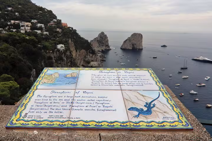 View of Capri's Faraglioni rocks with an informative sign about their history and significance in the foreground.