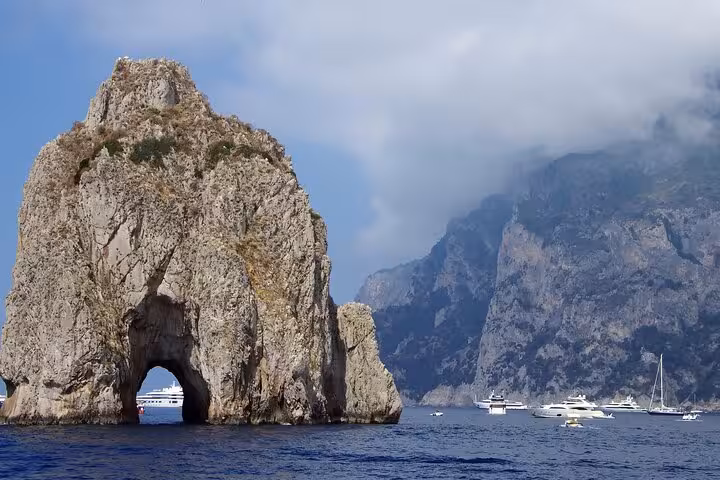 Scenic view of the majestic Faraglioni rock with yachts in the azure waters of Capri, perfect for a boat tour.