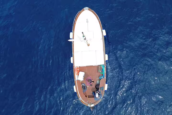 Aerial view of private classic gozzo boat cruising blue sea on a 3-hour Capri island tour
