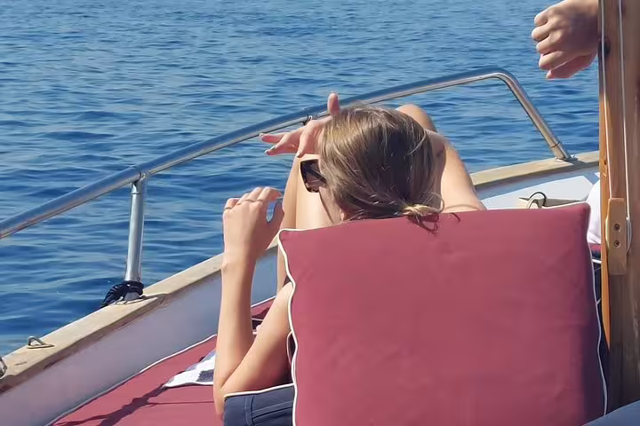 Relaxing on a private classic gozzo in Capri during a 3-hour island cruise, sunbathing on deck over blue water