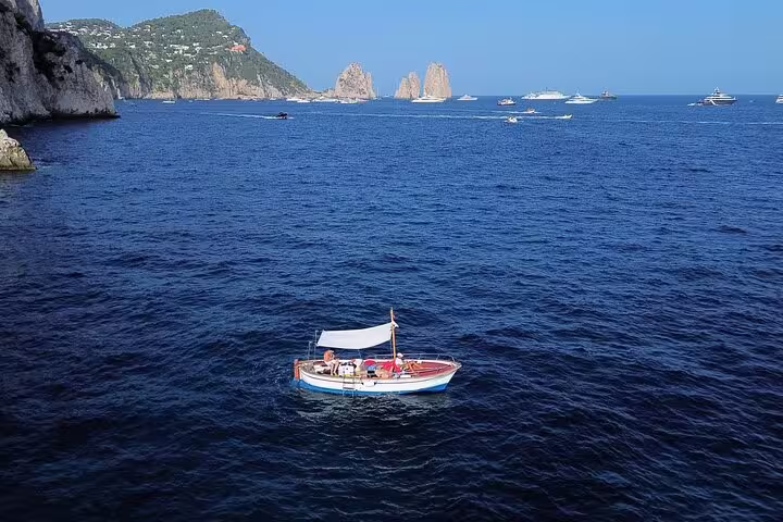 Private classic gozzo boat cruise off Capri with Faraglioni rocks in view on a 3-hour island tour