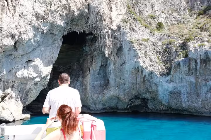 Tourists on a boat explore a dramatic grotto with turquoise waters during a Capri guided tour.