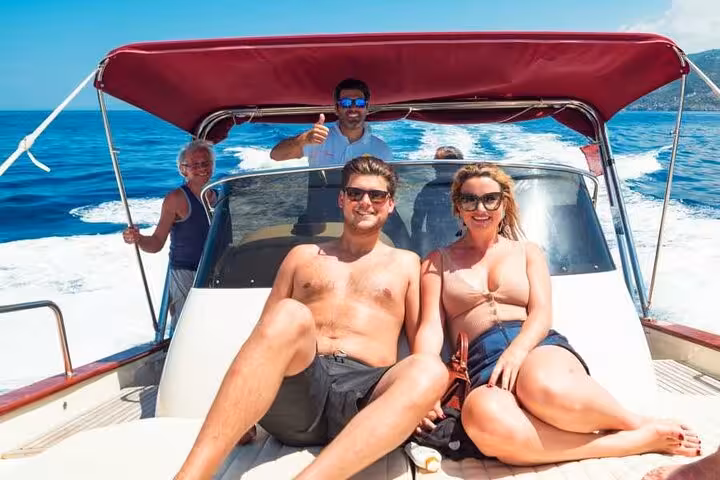 Relaxed tourists sunbathing on a boat during a Capri Island day trip, with stunning Mediterranean views.