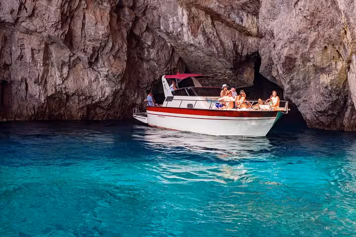 Visitors relax on a boat exploring the stunning turquoise waters and caves of Capri Island from Amalfi.