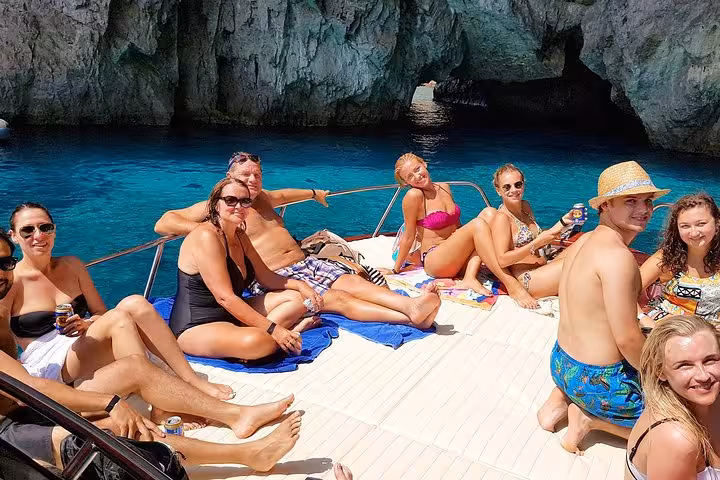 Group relaxing on boat during Capri Island day excursion from Sorrento, enjoying sun and stunning blue waters.