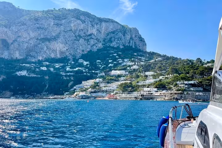 Scenic view of Capri's coastline with lush hills and villas from a boat during a full-day tour from Naples.