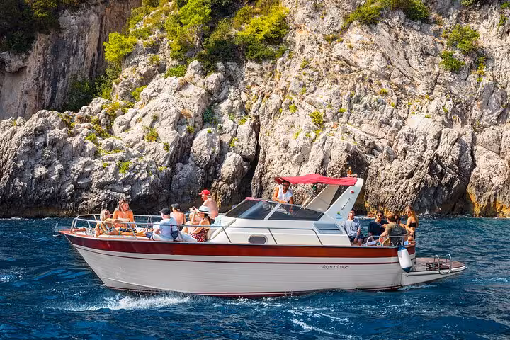 Small group relaxing on a boat near the scenic cliffs of Capri during a day tour from Naples.
