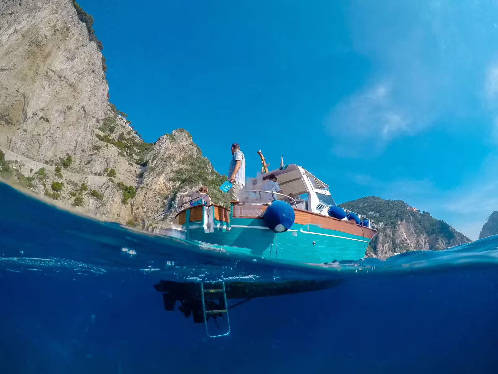 Tourists enjoying a scenic boat ride near Capri's stunning cliffs under a clear blue sky.