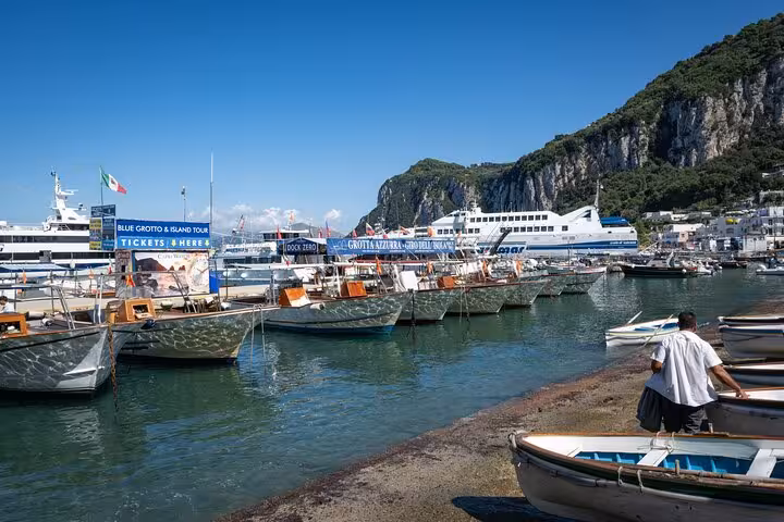 Docked boats in Marina Grande, Capri, ready for Blue Grotto and Faraglioni guided tours under a clear blue sky.