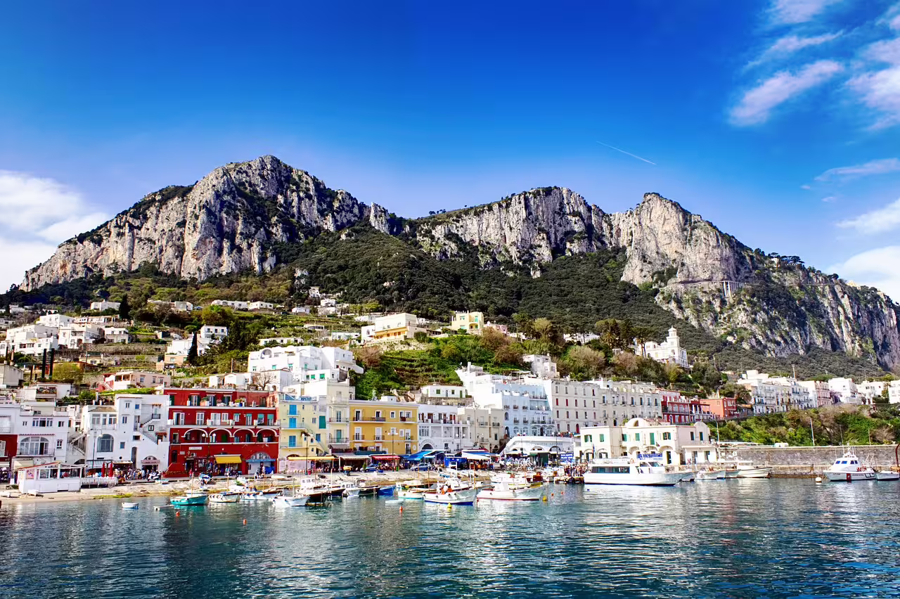 Colorful Marina Grande harbor and pastel houses beneath towering cliffs on a Capri daily tour from Naples or Sorrento