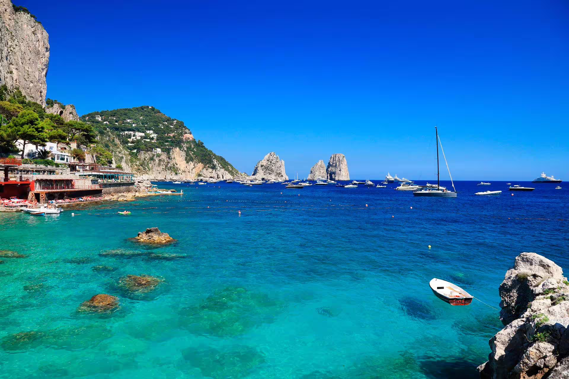 Capri Marina Piccola bay with turquoise sea and Faraglioni rocks, small group day trip from Naples by ferry